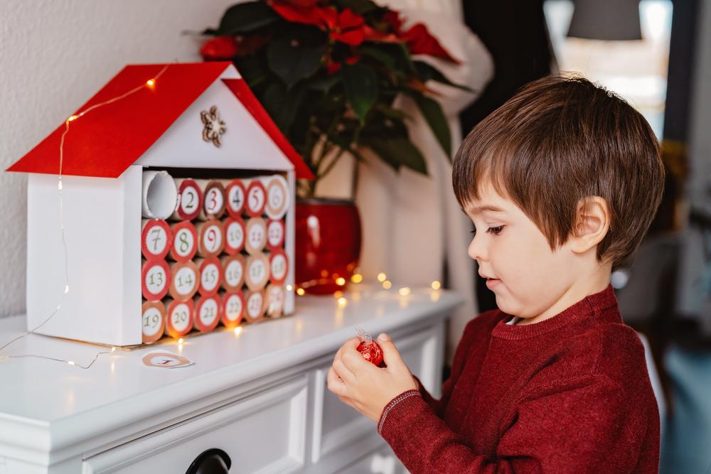  child taking chocolate opening first day in handmade advent calendar made from toilet paper rolls