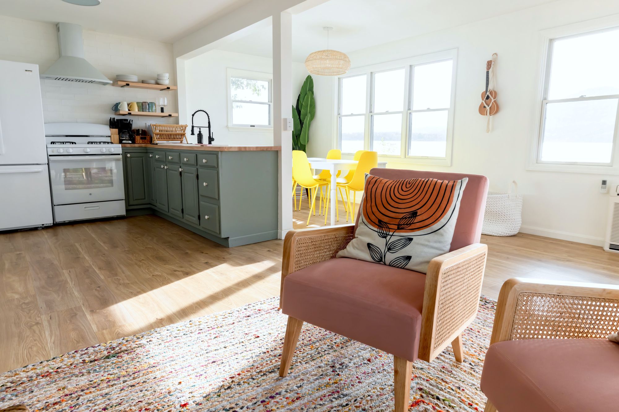 Interior de uma casa pequena com ambientes integrados, mostrando uma cozinha moderna com armários em tom verde-oliva e eletrodomésticos brancos. Foto: Andrea Davis / Pexels
