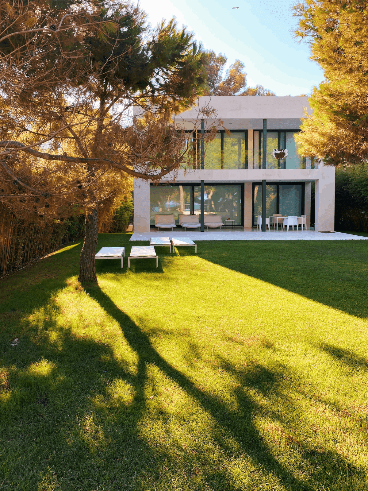 diseño de casa moderna de dos pisos con ventanales y jardín con cesped