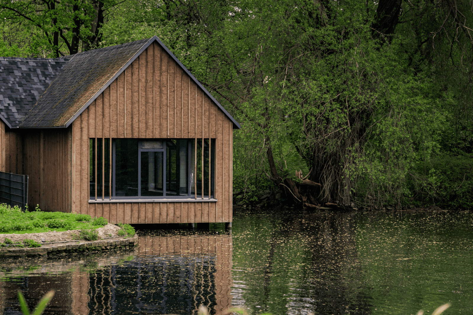 diseño de casa ecológica de madera con ventanales y lago