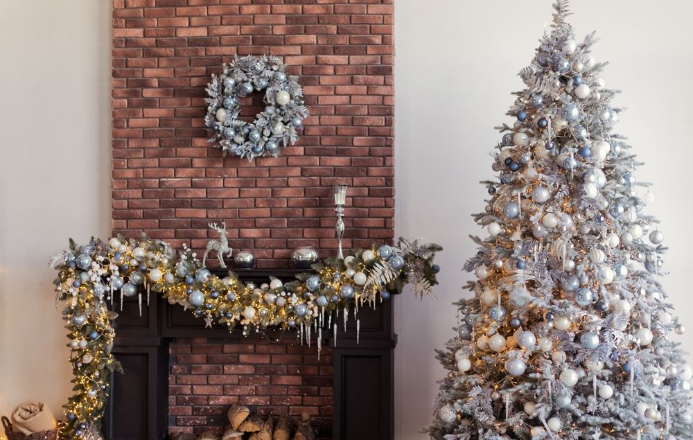 Salon avec cheminée en briques et sapin de Noël avec décorations argentées et bleues