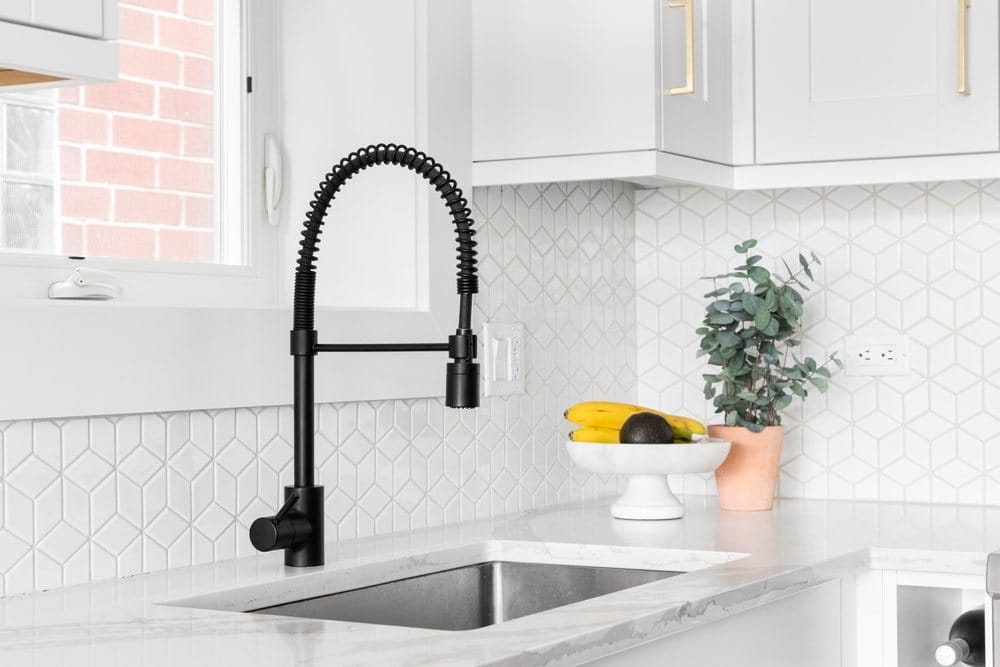 Kitchen sink with a black faucet and mosaic tile backsplash