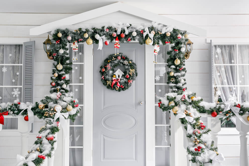 porche d'une petite maison avec une porte décorée d'une couronne de Noël