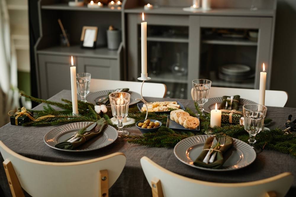 cozy table setting decorated for Christmas with candles lit in grey tones,