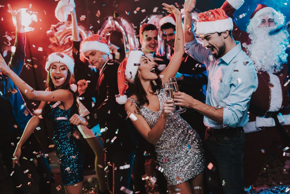 Happy people dancing at a New Year's party in Santa hats