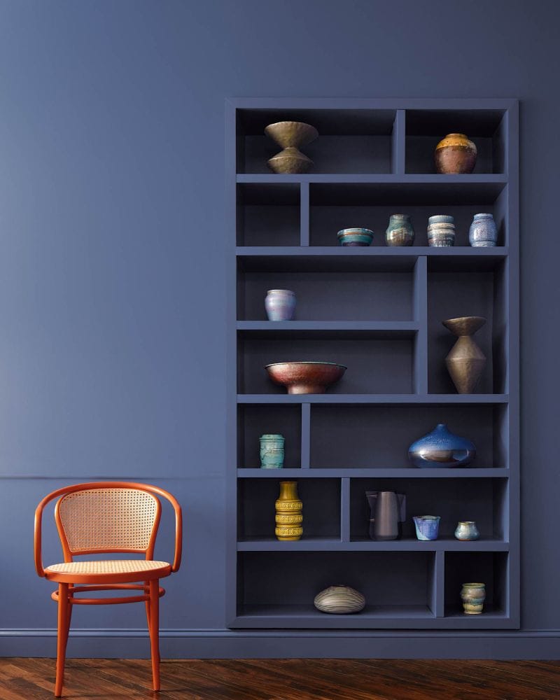 A modern red office chair sits in a home office painted in Blue Nova 825, with built-in shelving, cabinetry.