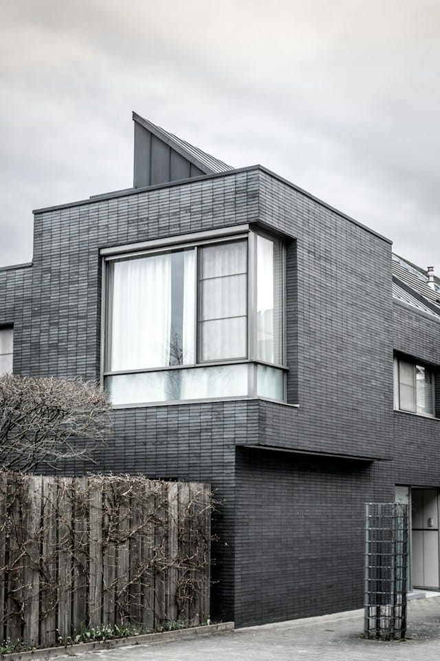 fachada de casa de dos pisos de azulejos negros con ventanales