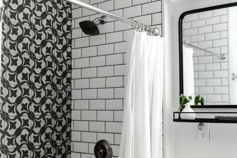 banheiro pequeno com azulejos brancos e com estampas