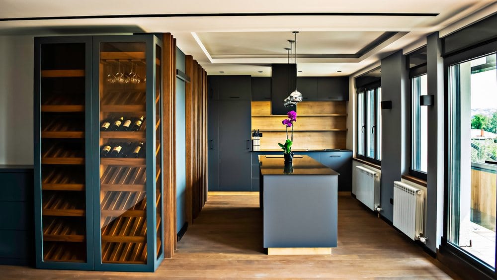 современная кухня с вертикальной витриной, деревянной винной стойкой и кухонным островом.
