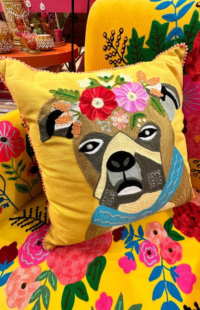 pillow with an embroided dog face on a flowery couch