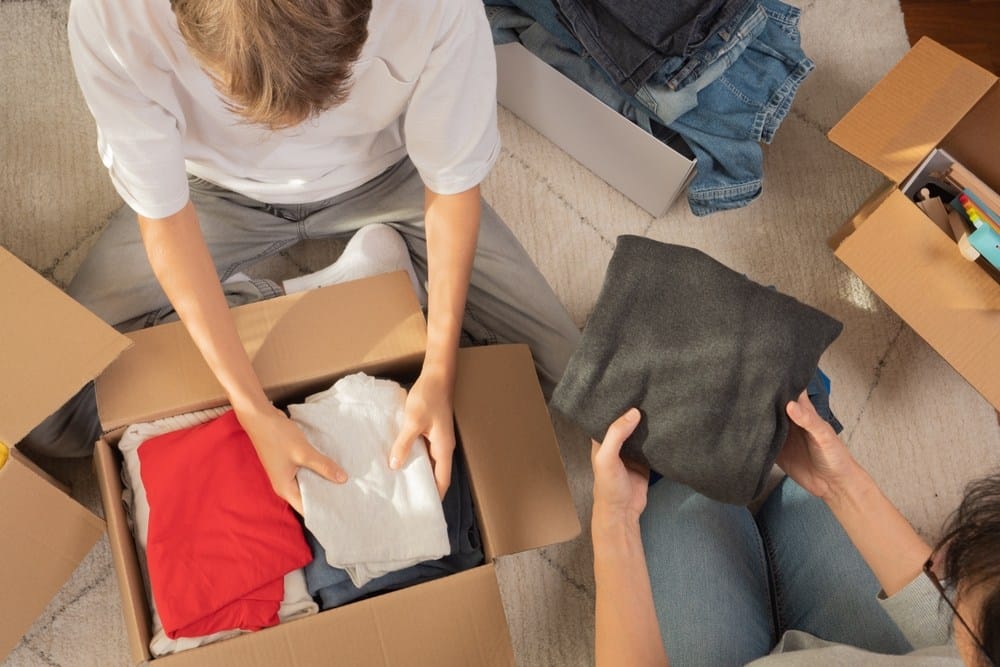 Woman and child sorting clothes and packing into cardboard box