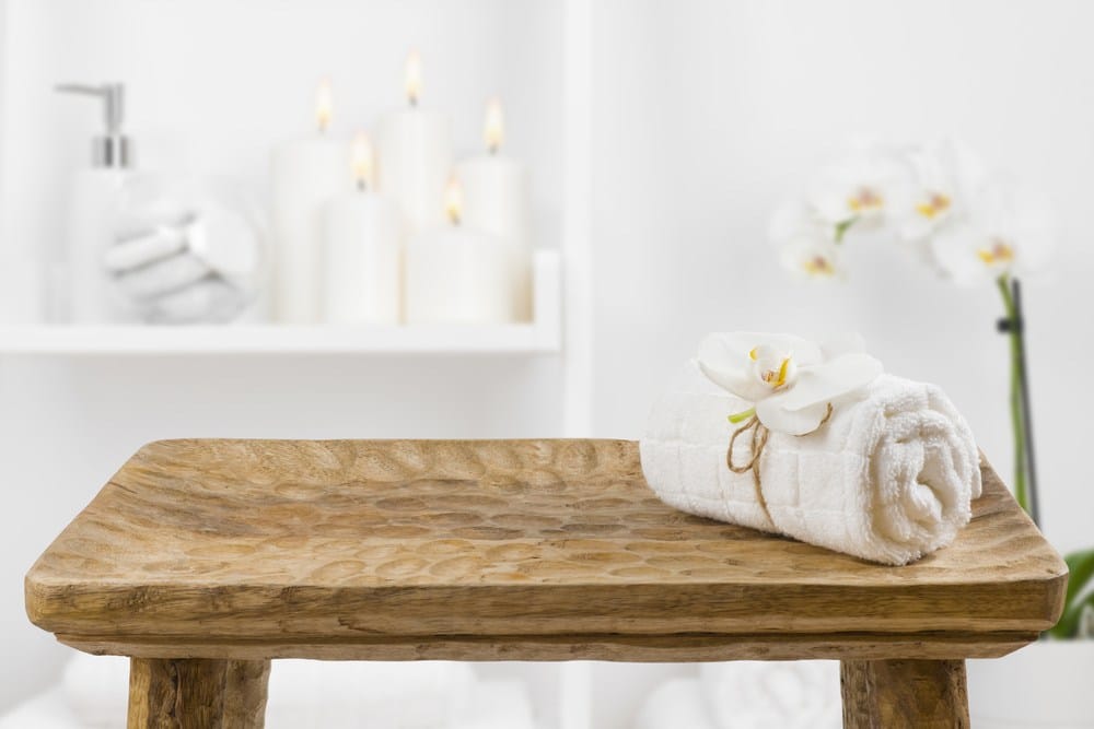 Drewniany stolik z ręcznikiem spa na rozmytym tle półki łazienkowej