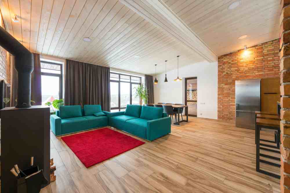 casa térrea de madeira com sofá azul e tapete vermelho