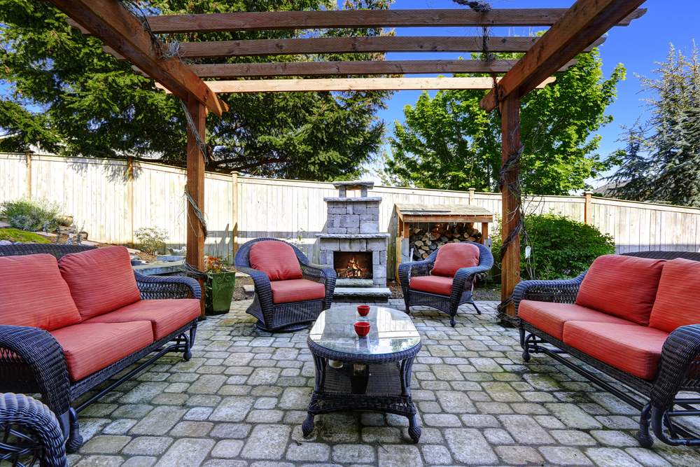 Backyard cozy patio area with wicker furniture set and brick fireplace