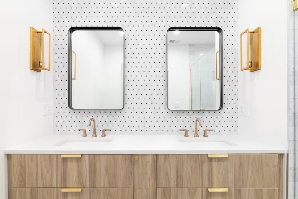 łazienka z pływającą szafką z drewna, złotym kranem i światłami, mozaikową ścianą, oraz prostokątnymi lustrami