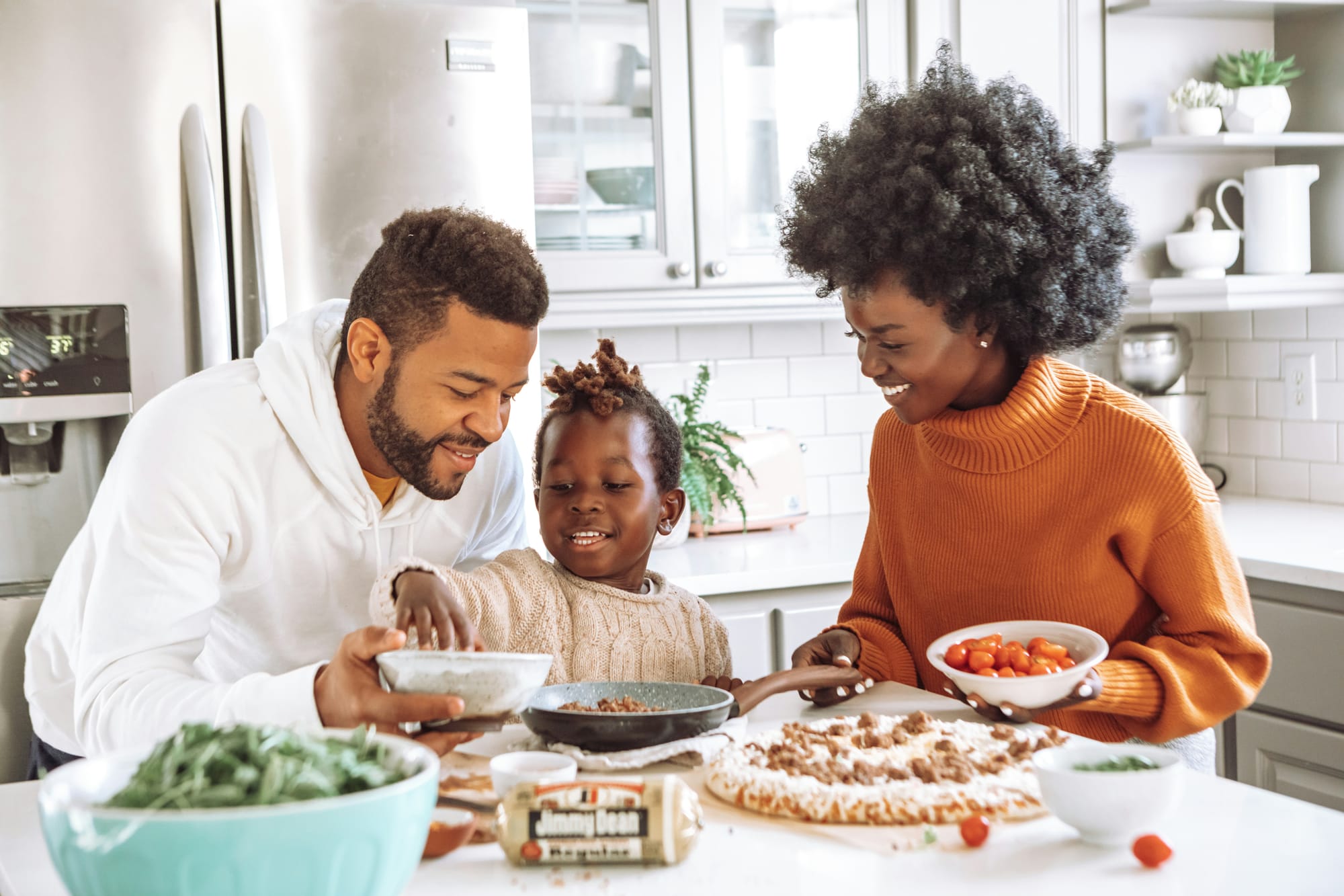 famille afro-américaine de 3 personnes préparant une pizza dans la cuisine