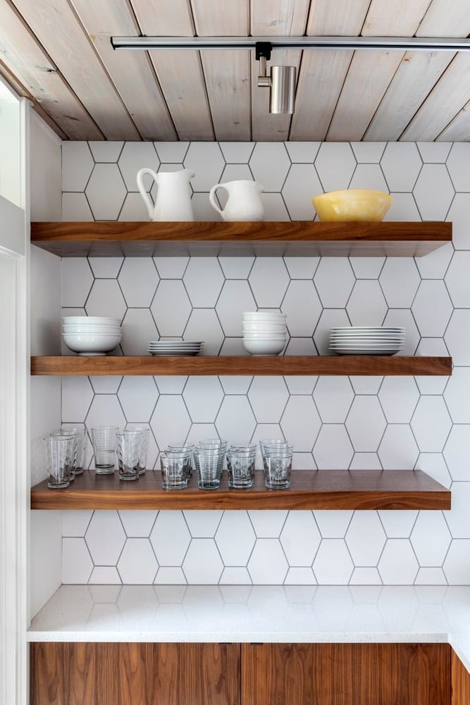 Floating modern kitchen shelving with plates and glasses.