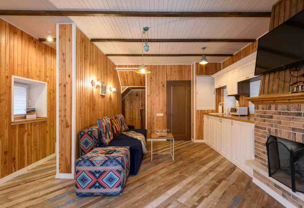 sobrado de madeira pré fabricado com sofá azul, cozinha e espaço para fogueira