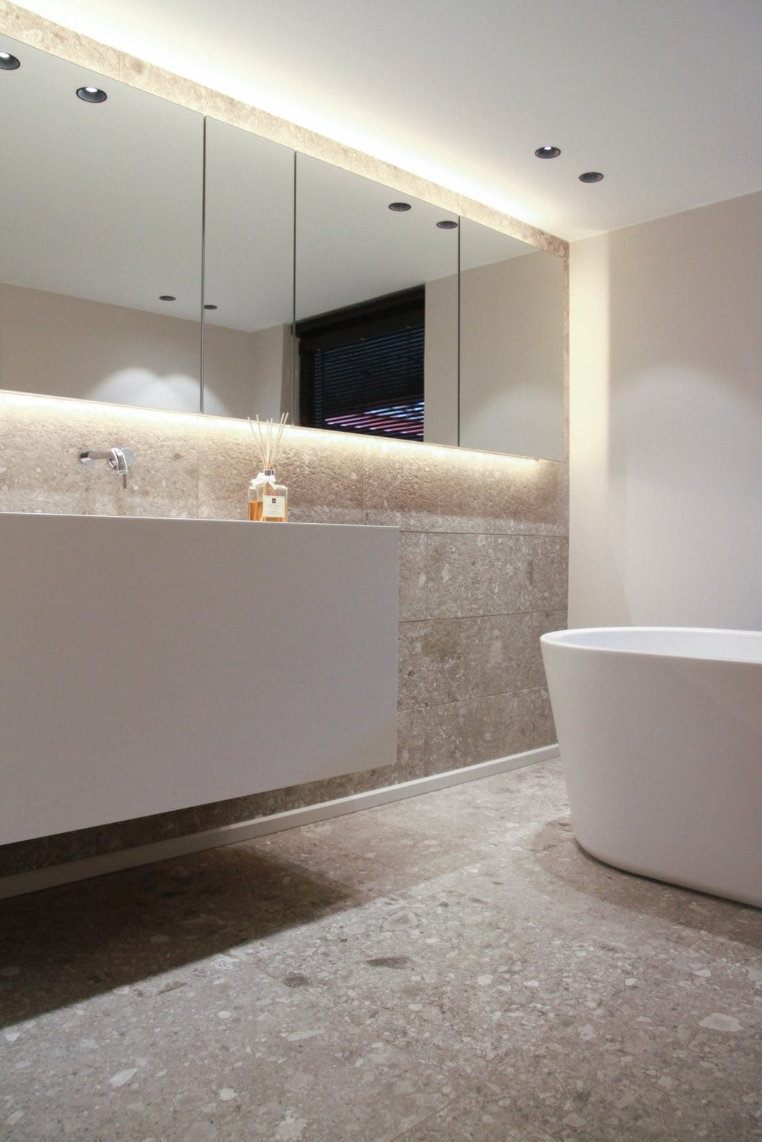 cuarto de baño moderno con terrazzo en suelos y paredes y muebles blancos