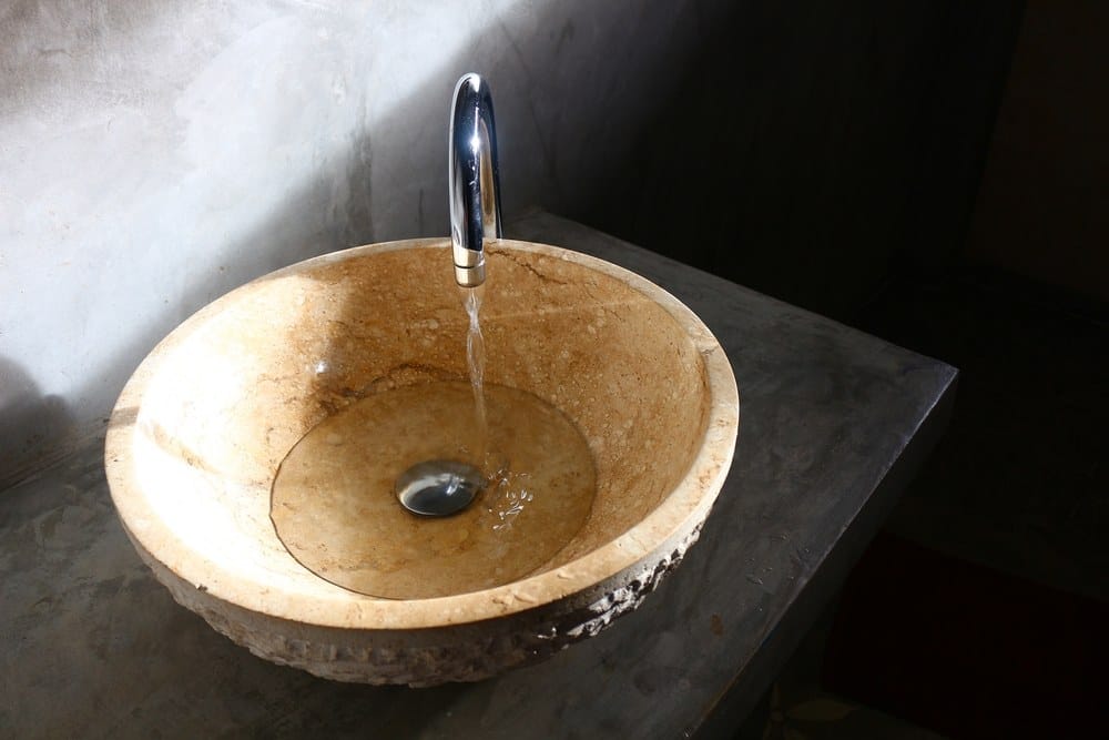 Okrągła umywalka przypominająca kamień w nowoczesnej łazience