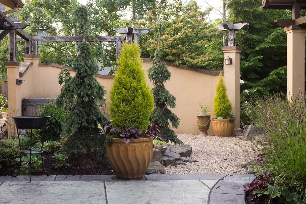 A pebbled walkway at the entrance to a backyard retreat filled with perennials inspired by Tuscany.