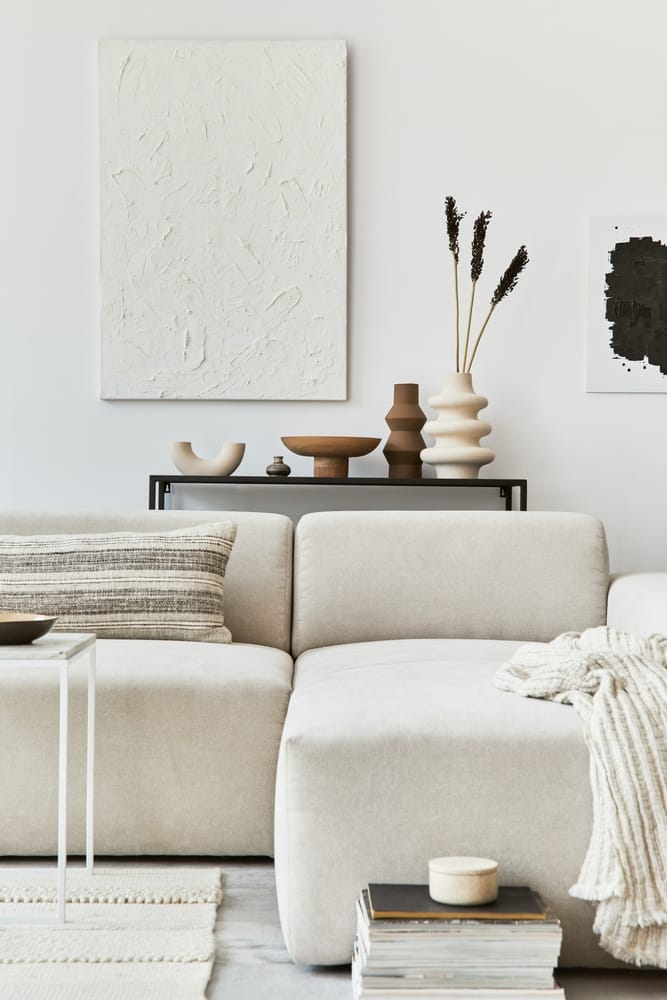 soggiorno con un quadro alla parete, vasi e un grande divano bianco