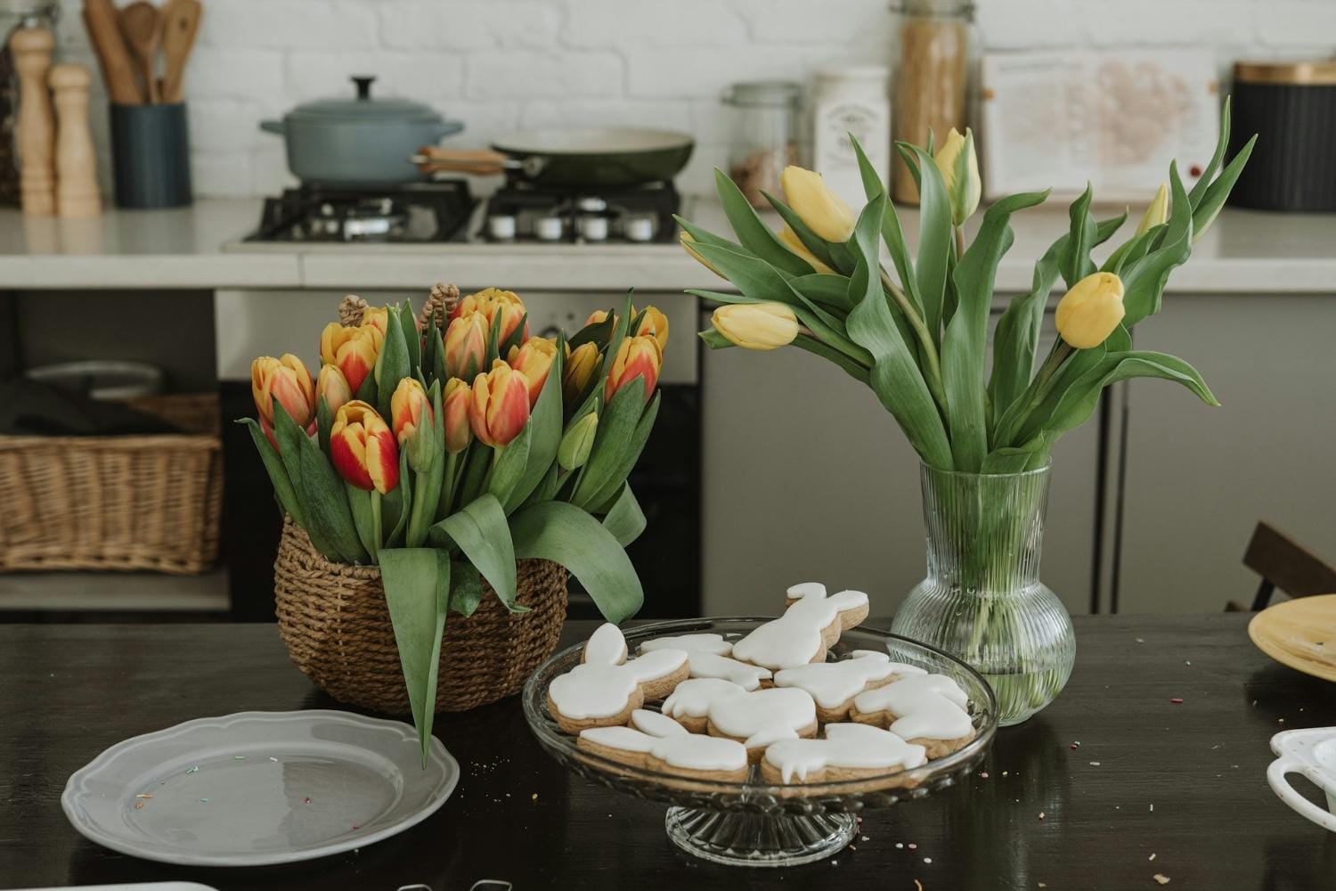 zwei Tulpensträuße und Kekse in Hasenform auf einem Ostertisch