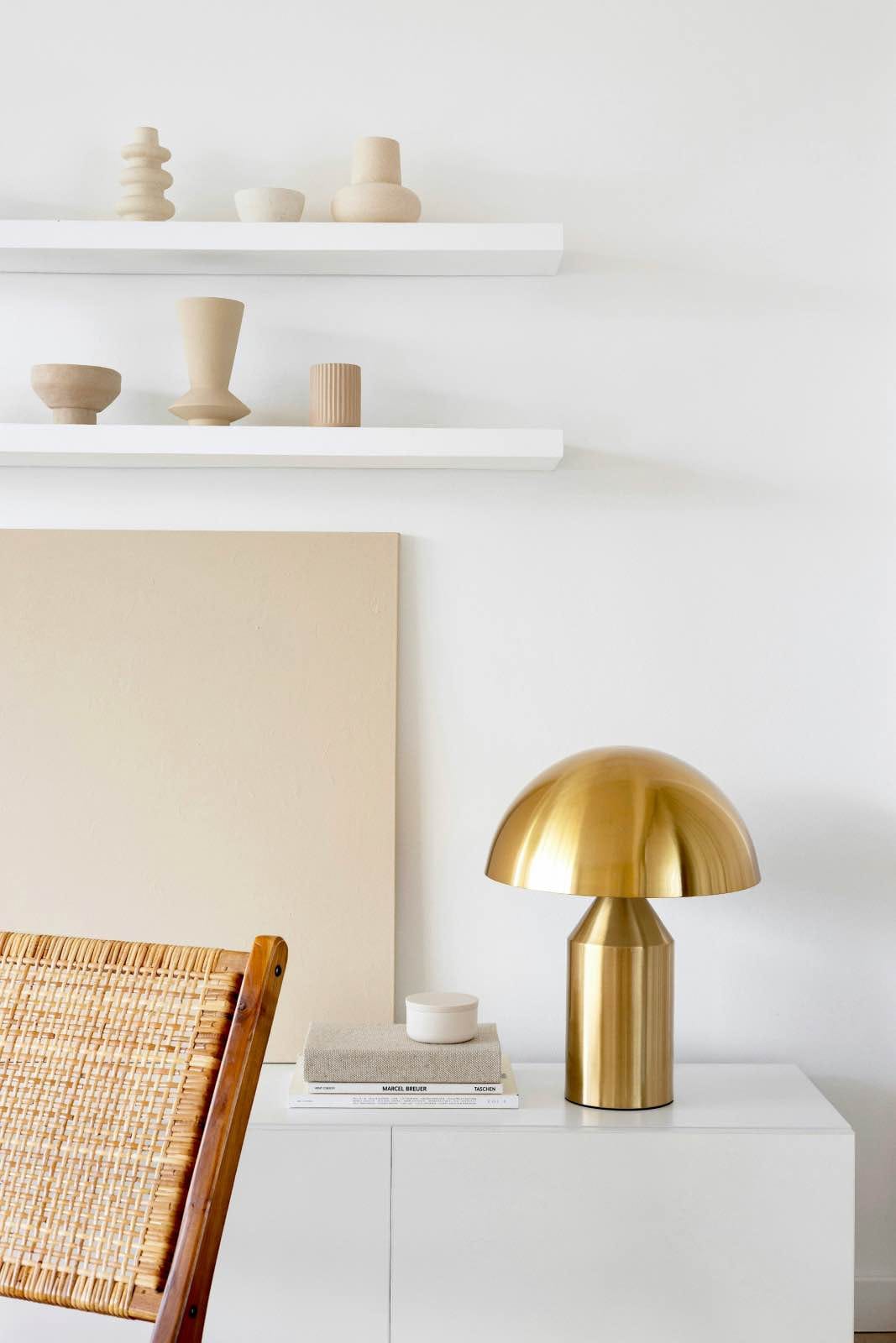 A gold lamp on a white dresser with books
