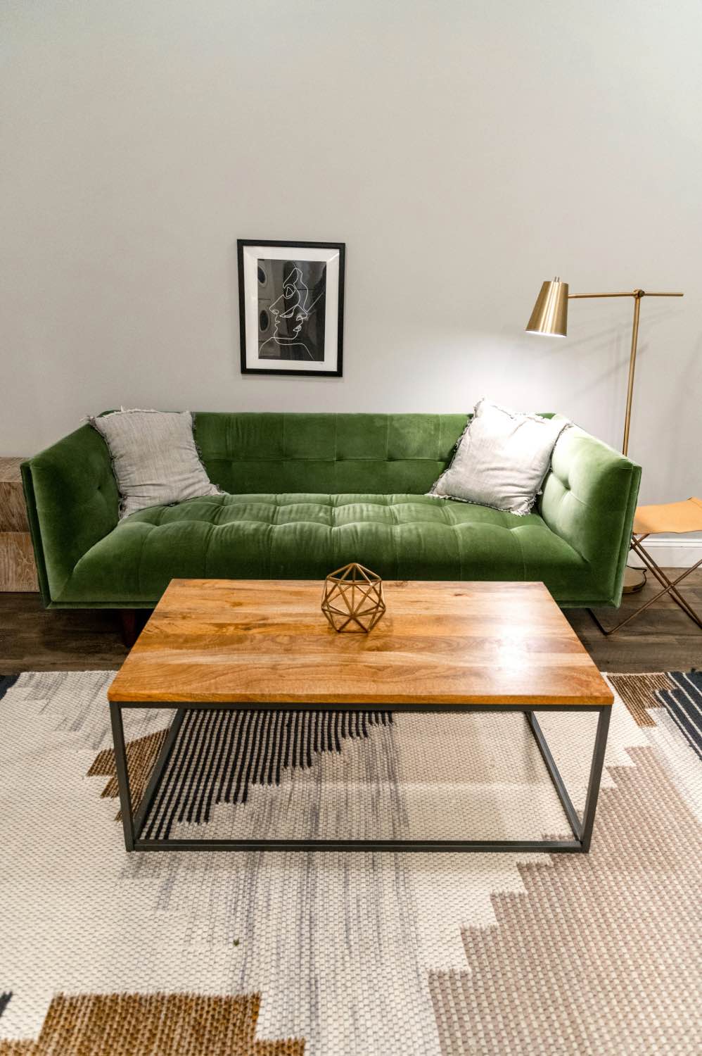 гостиная с зеленым диваном, деревянным столом и бежевым ковром