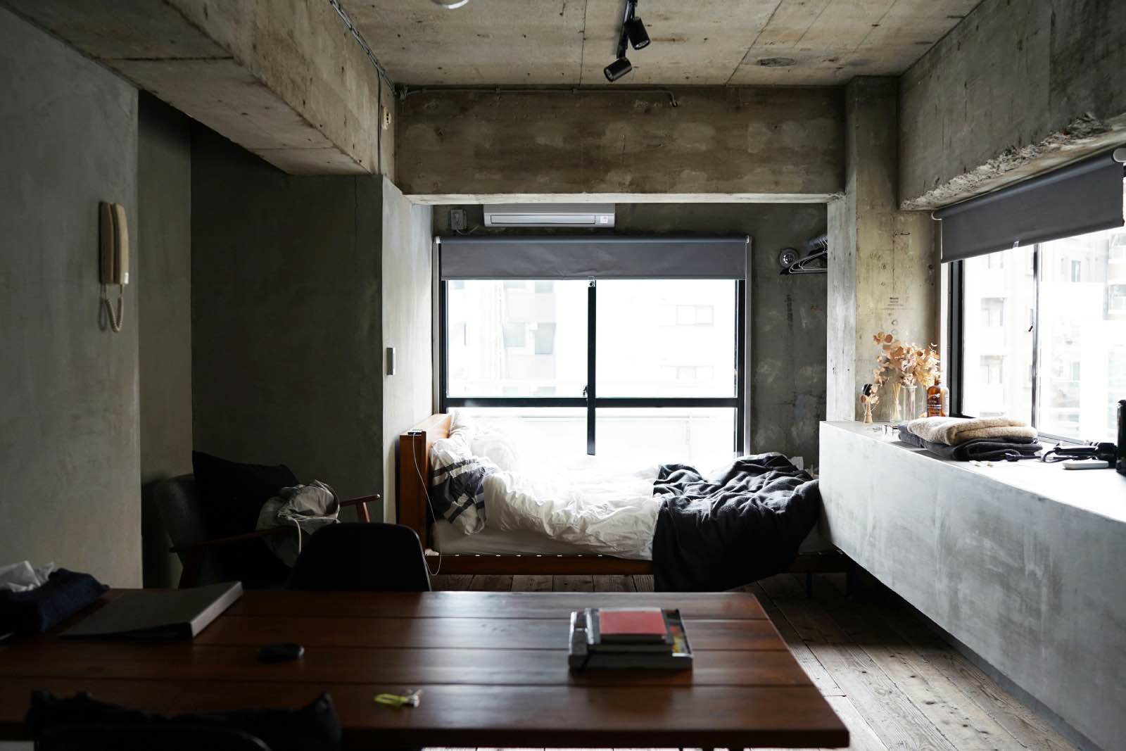 Apartamento tipo estudio de estilo industrial de hormigón con cama y mesa y sofá