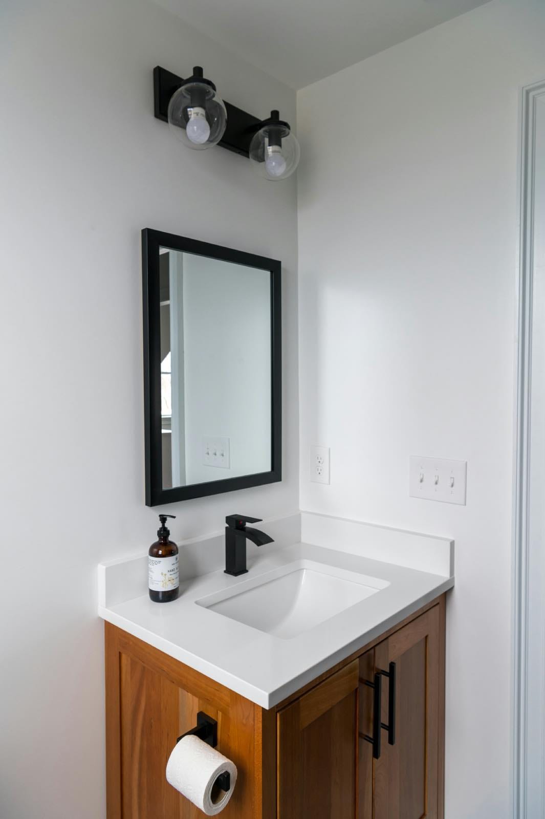cuarto de baño blanco y negro pequeño con mueble de madera y espejo