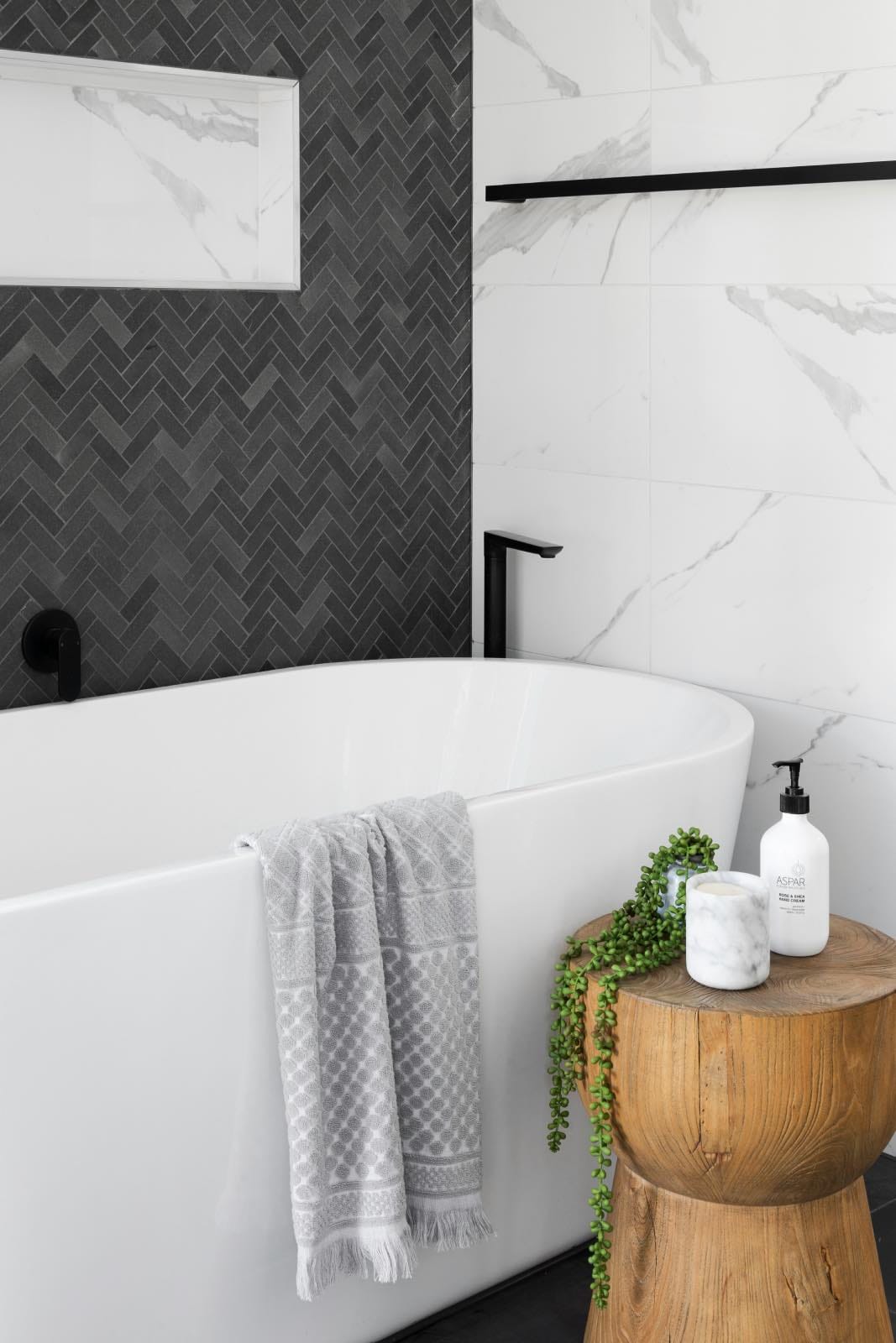 cuarto de baño blanco y negro con bañera, pared de mármol y decoración madera