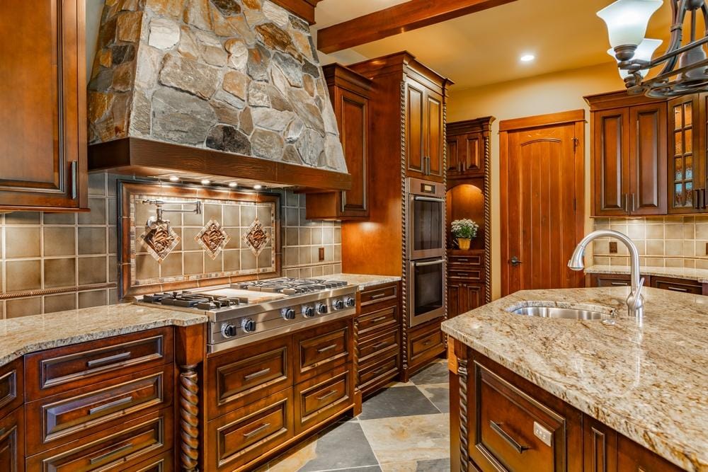 Luxurious dark wood kitchen with rich wood cabinets granite counter tops slate floor tile stone range hood