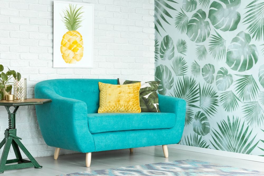 chambre ludique avec un canapé bleu vif et des motifs d'ananas sur le mur et les coussins