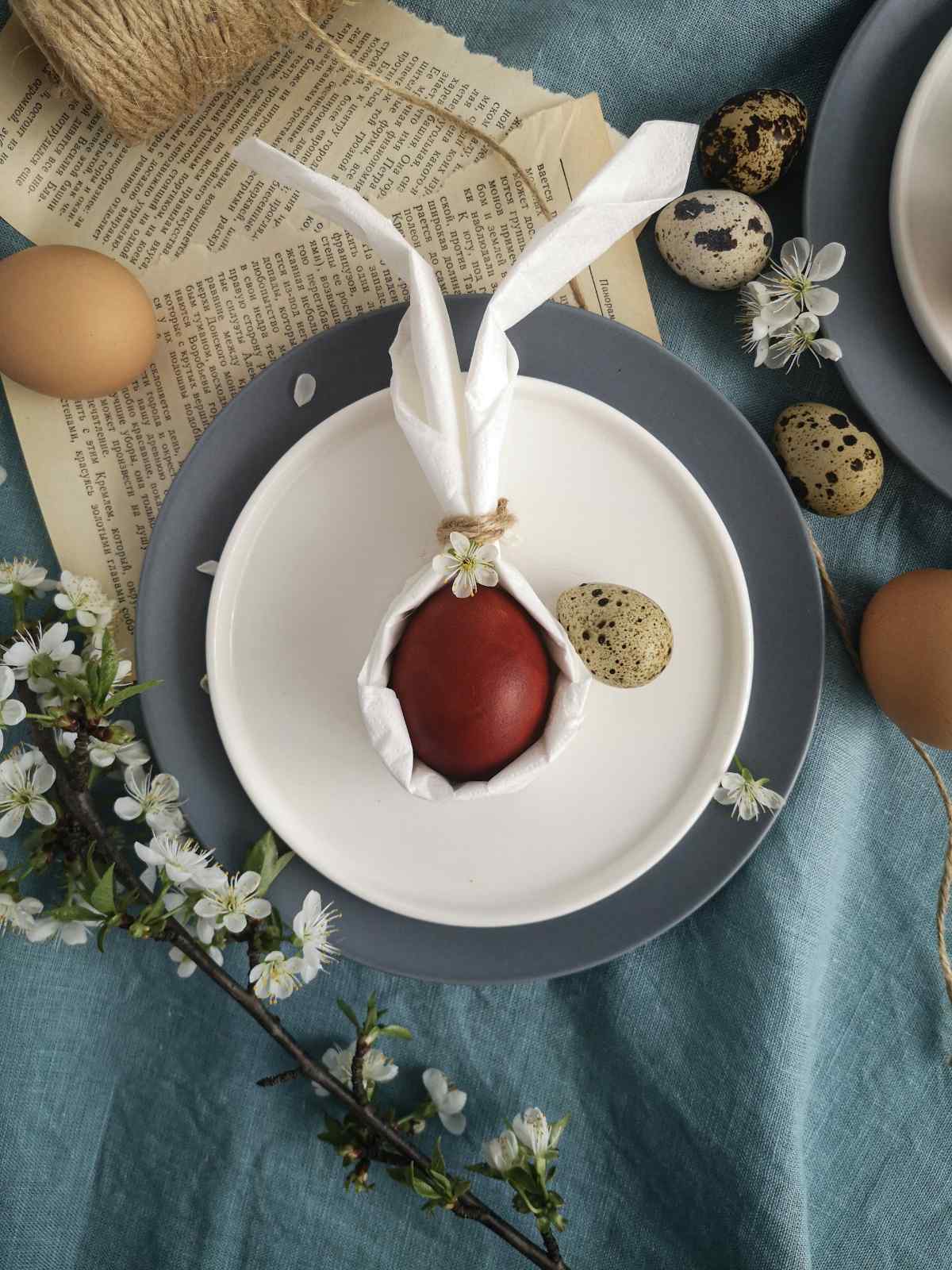 Tischdekoration zu Ostern mit Eiern und einer gefalteten Serviette in Form eines Hasen