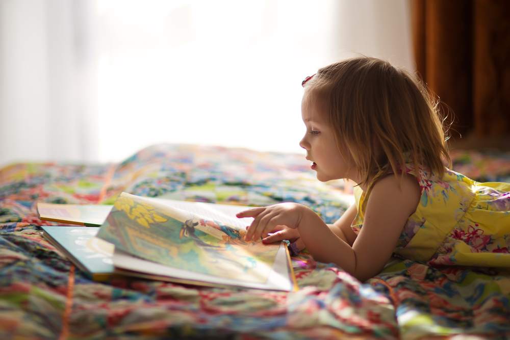 menina lendo livro no cantinho de leitura