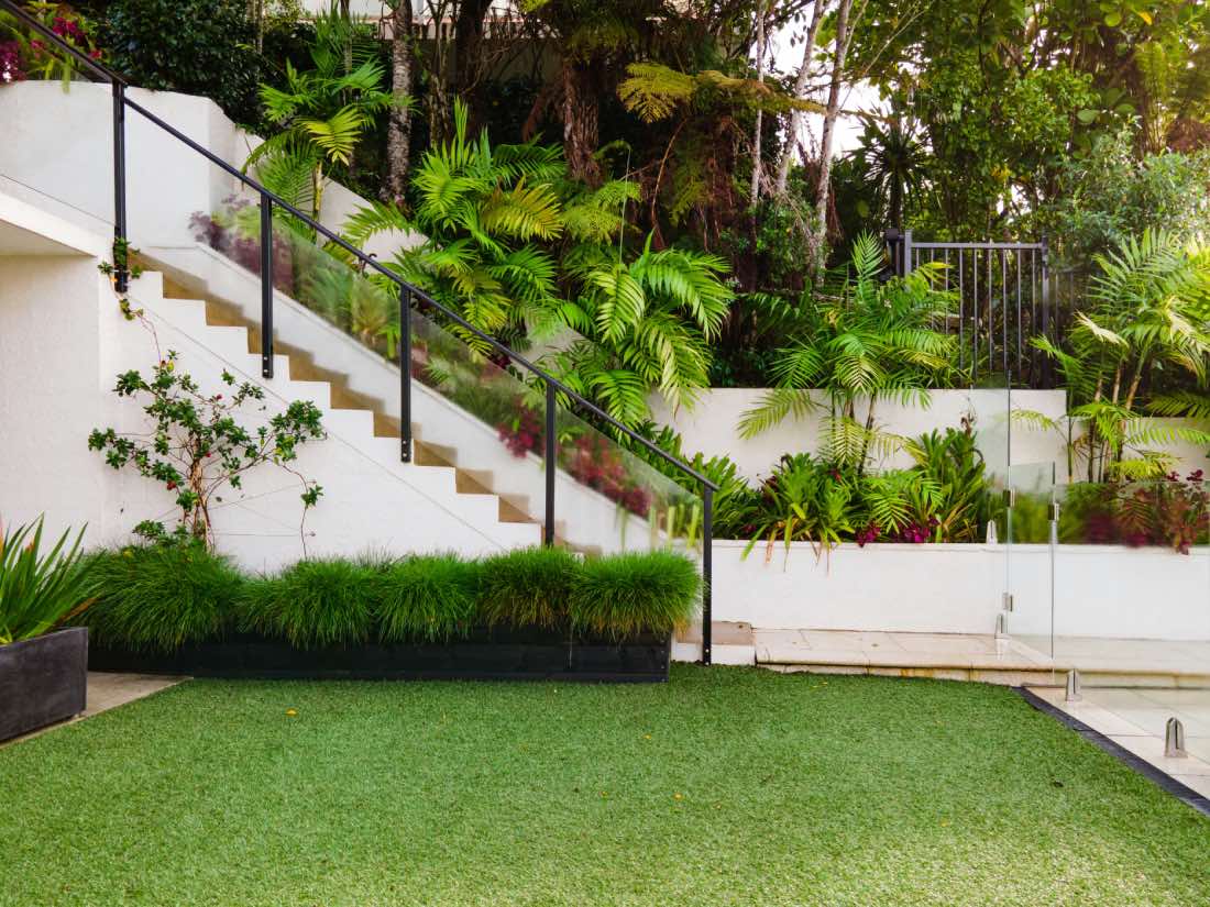 jardín de diseño con escaleras, muros blancos, césped, plantas palmeras