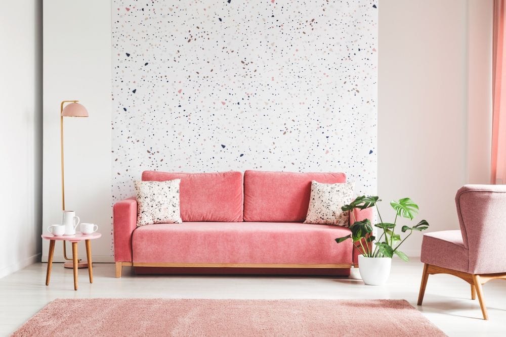 Rosarote Zimmerecke mit gepunkteter Tapete und einem rosa Sofa