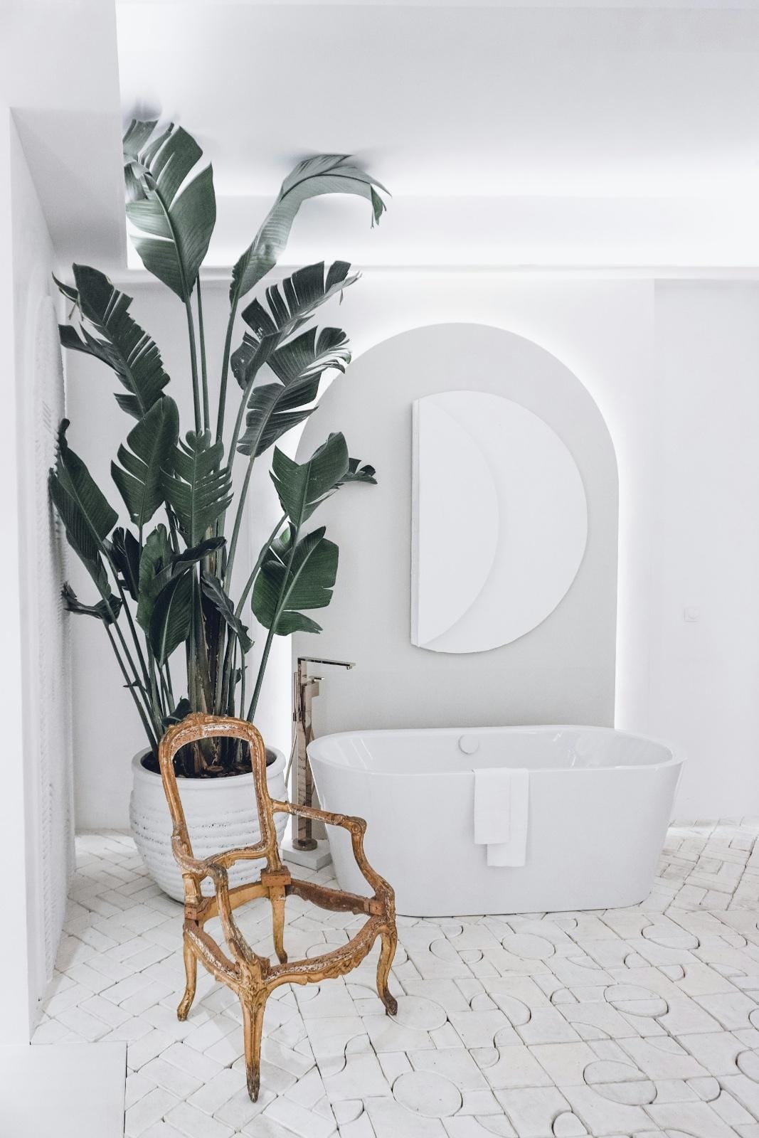 weißes Badezimmer mit einer weißen Badewanne, einem goldenen Stuhl und einem Spiegel