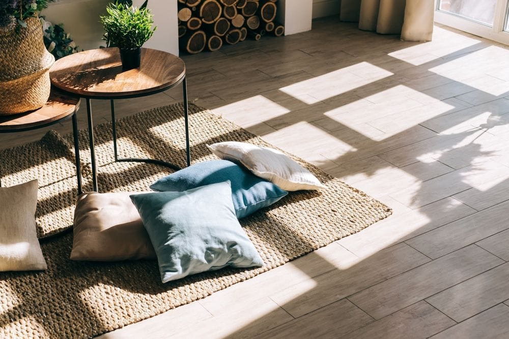 Juteteppich und Kissen auf dem Boden eines rustikalen Wohnzimmers