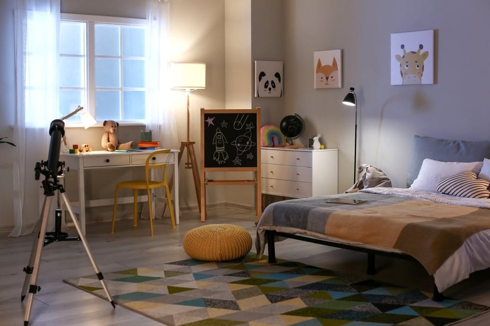 chambre d'enfant avec un lit, des posters, un télescope et un bureau