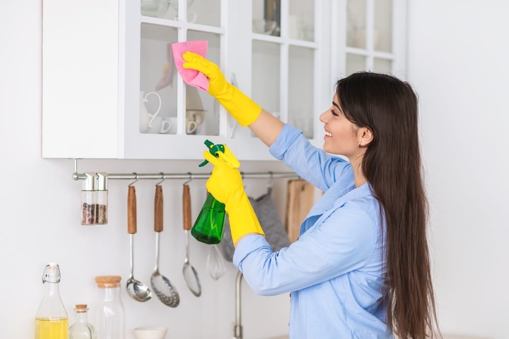 femme souriante nettoie le placard dans la cuisine