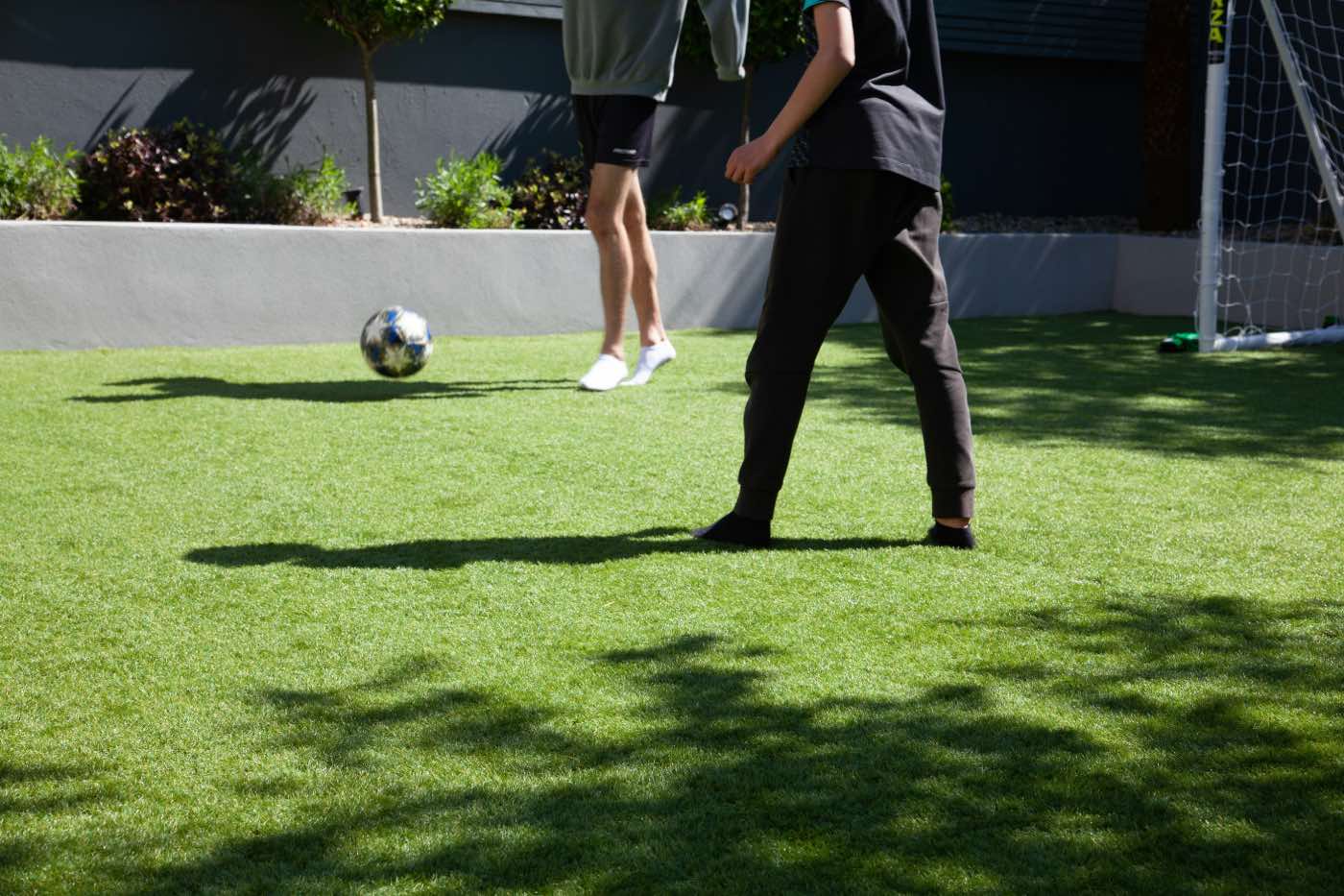 jardín con césped artificial para jugar al fútbol, niños jugando