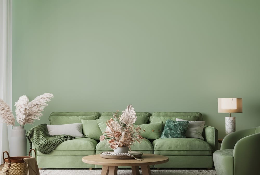 salon élégant avec des murs verts, un canapé vert, des coussins en velours vert et une table basse marron