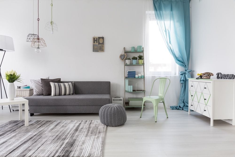 salon avec des rideaux bleus, un canapé gris, une commode avec un signe de dream