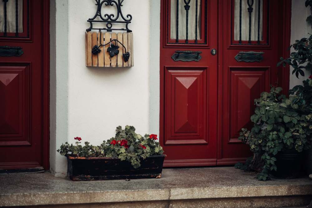 portão de madeira pintado de vermelho de casa simples com decoração de plantas e flores na frente