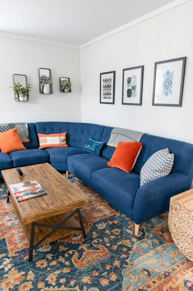 sala decorada com sofá azul, almofadas laranjas e tapete com a mesma paleta de cores