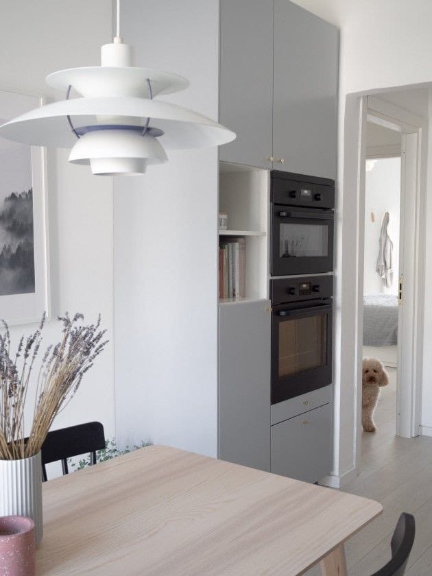 cocina decorada en estilo escandinavo con muebles azul claro y mesa de madera