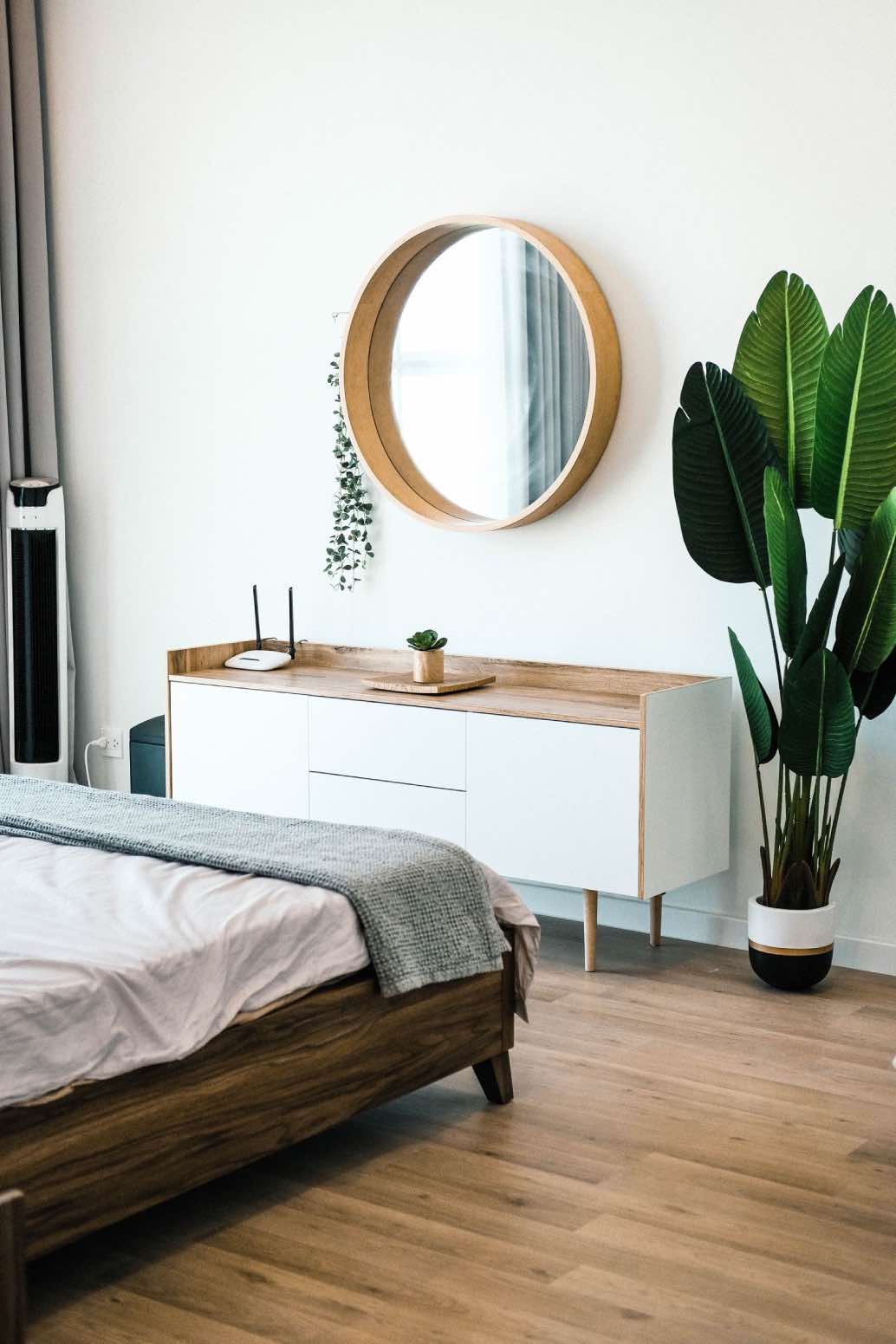 dormitorio de estilo escandinavo con planta y espejo