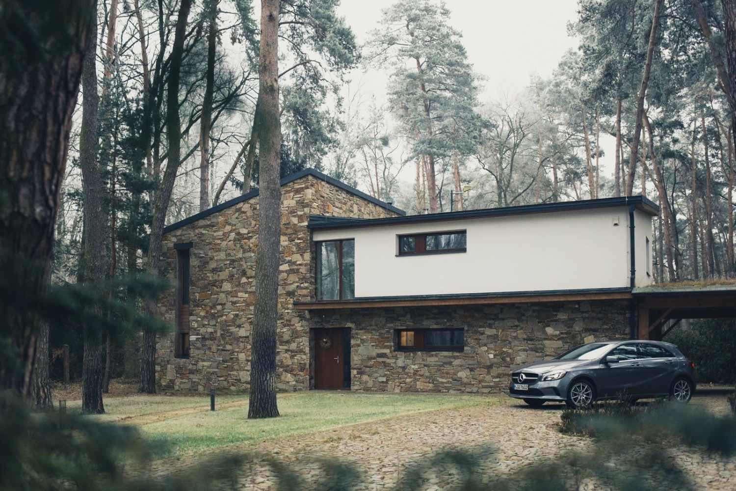 fachada de casa moderna rústica en el bosque con coche